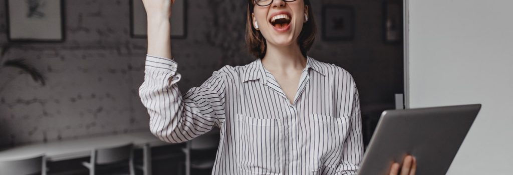 4 girl happily screams makes winning hand gesture holding laptop posing office against background board